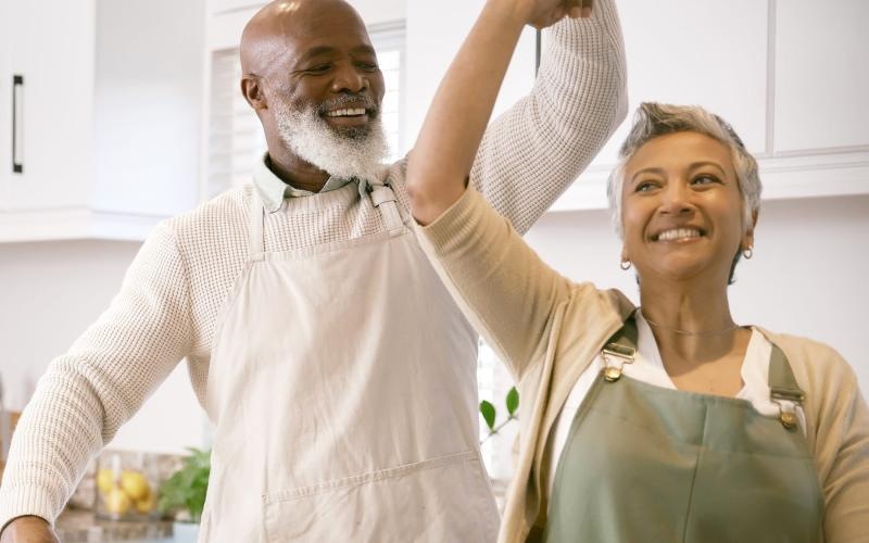 a man and woman smiling and dancing in the kitchen