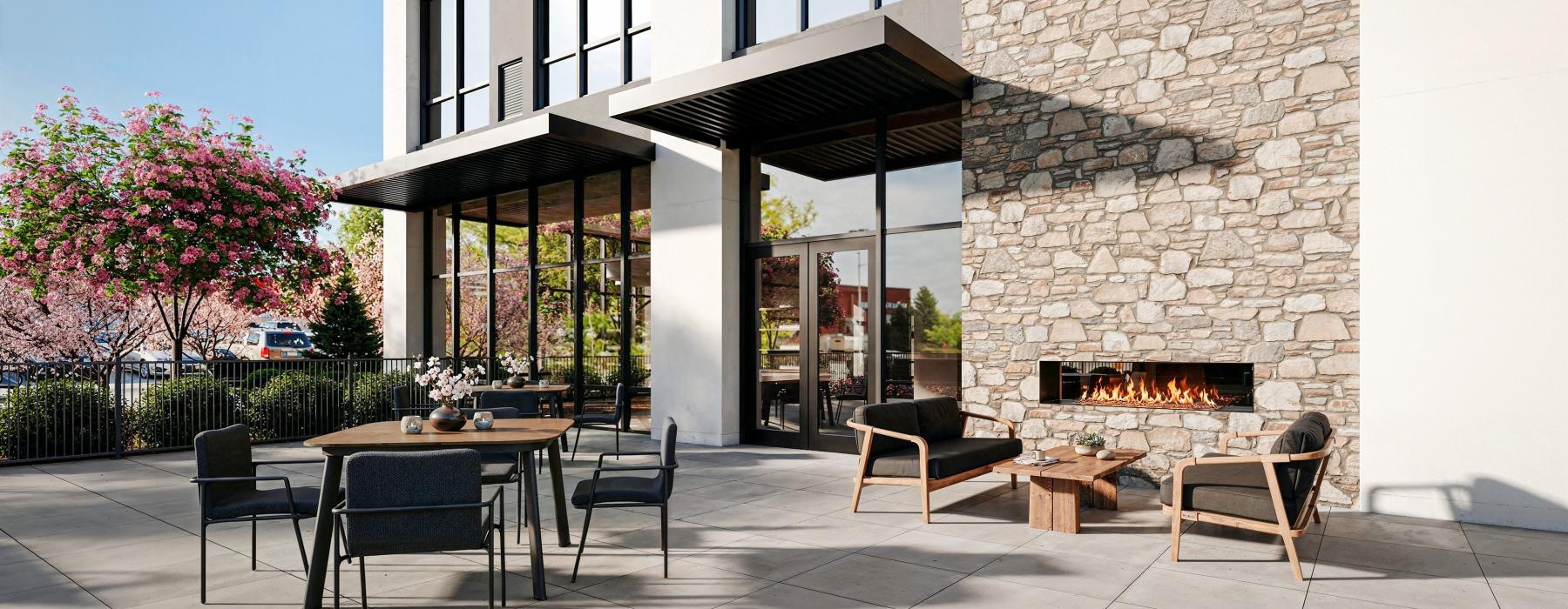 a patio with a table and chairs outside a building and a fireplace
